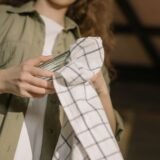 Pensule de machiaj spălate, așezate la uscat pe un prosop alb, lângă un săpun și un bol cu apă
