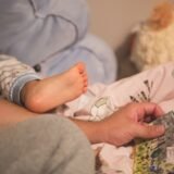 Părinte care citește o poveste unui copil în pijama, la lumina caldă a unei veioze, în camera copilului